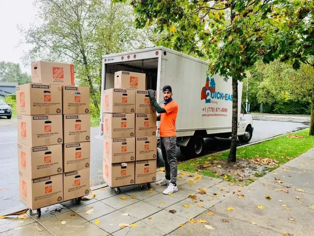 A Quick & Easy Moving crew member wheeling stacked cartons to the moving truck at the kerb