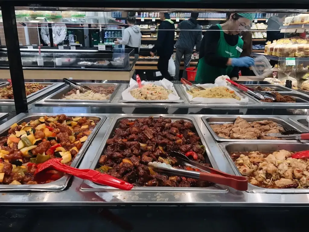 Trays of hot cooked dishes on a supermarket food bar counter