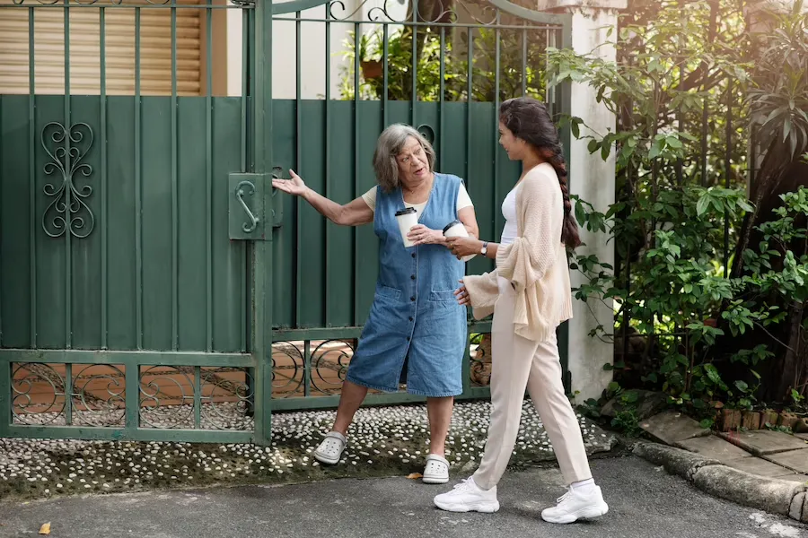 Moving-New-Neighborbood Two neighbours chatting over coffee at a front gate on a residential street