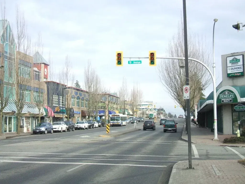 South-Surrey Shops, parked cars and a transit bus along 19 Avenue in South Surrey