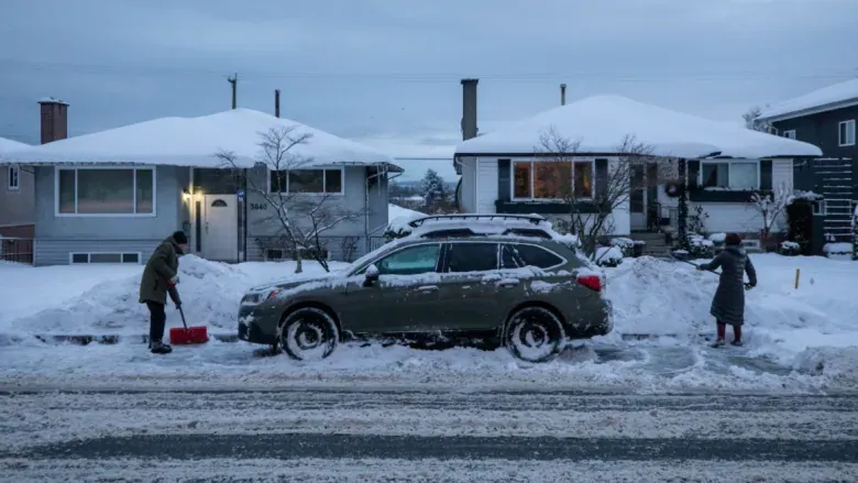 snow-footwear Residents shovelling snow around a parked car on a snow-covered residential street